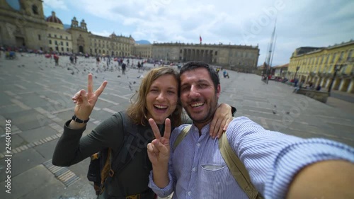 Happy young couple travelling in Colombia taking a selfie photo in the capital Bogota, smiling in the main square Bolivar in Calendaria district