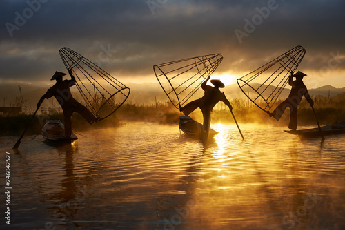 Valokuvatapetti Silhouettes of three fishermen on Inle lake Myanmar