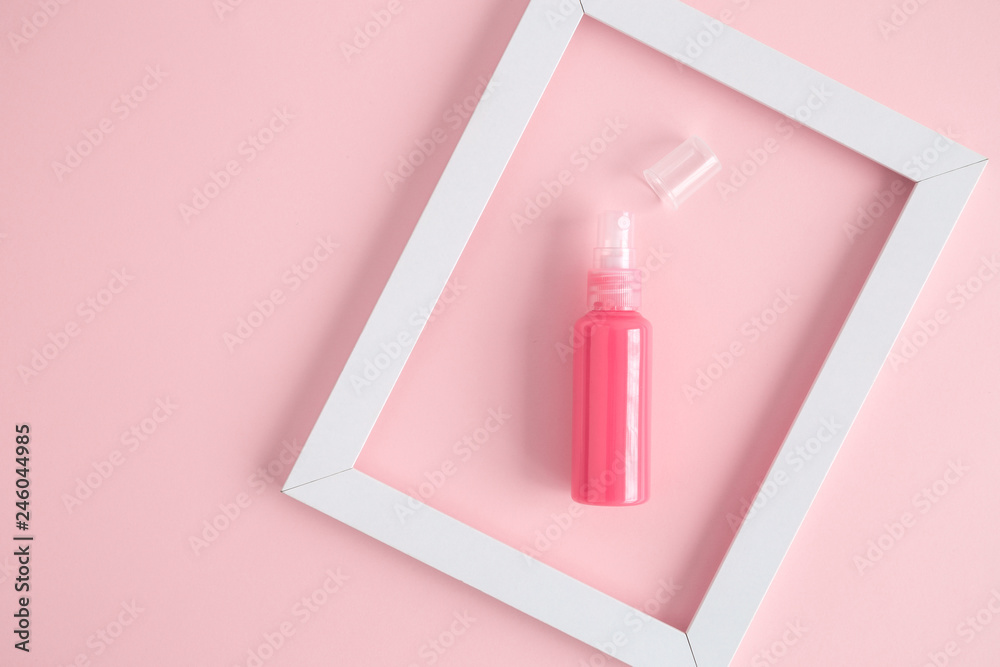 High angle view of perfume bottle and picture frame abstract against pink background. High angle view of perfume bottle and picture frame abstract against pink background.