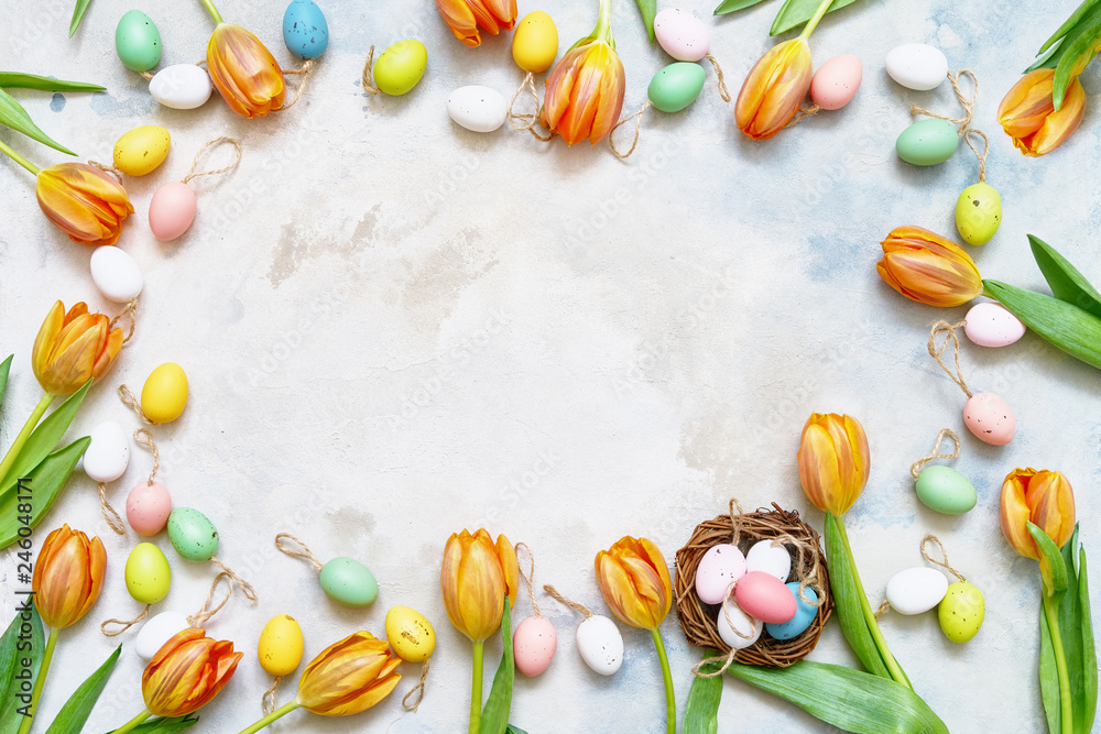 Easter background. Decorative Easter eggs and spring tulips on colorful background. Copy space, top view.