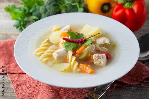 Chicken soup with noodles and vegetables, rustic wooden background. Healthy homemade food.