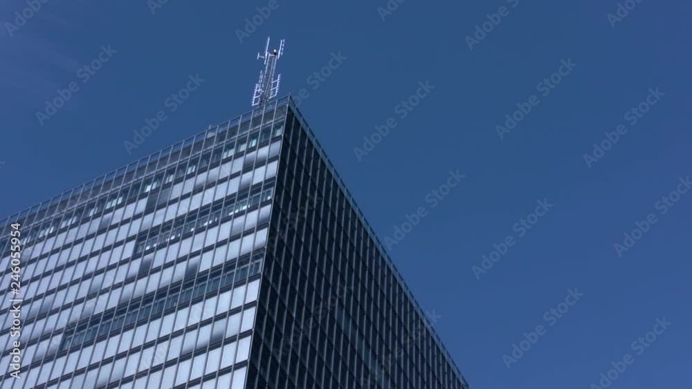 An antenna high on top of a modern skyscraper. Bright blue clear sky ...