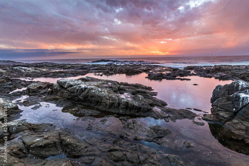 Sunset at Anzota Caves seafront walk. The rays of light coming from the sun illuminating the clouds and with amazing reflections over the Pacific Ocean sea waters while the waves moves over the rocks Sunset at Anzota Caves seafront walk. The rays of light coming from the sun illuminating the clouds and with amazing reflections over the Pacific Ocean sea waters while the waves moves over the rocks