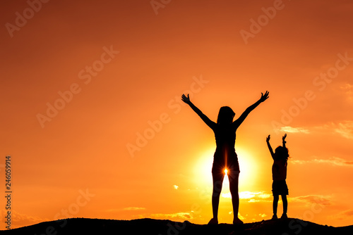 Silhouette mother and daughter on the mound at the sky sunset.