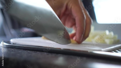 Chef chopping garlic with knife on cutting board in kitchne of motorhome - Close Up photo