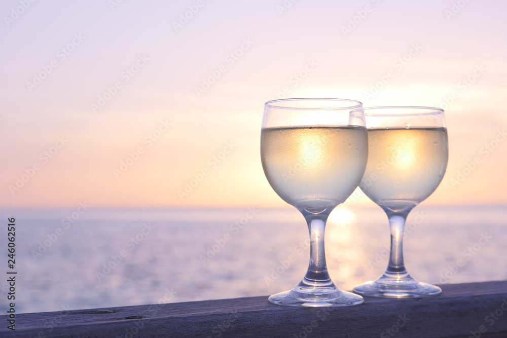Romantic luxury evening on cruise yacht with winery setting. Glasses, white wine and tropical sunset with sea background. Vacation relax time on the sea of Maldives island.