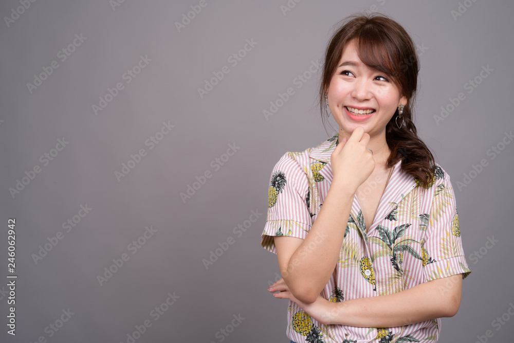 Portrait of young happy Asian tourist woman smiling and thinking Portrait of young happy Asian tourist woman smiling and thinking