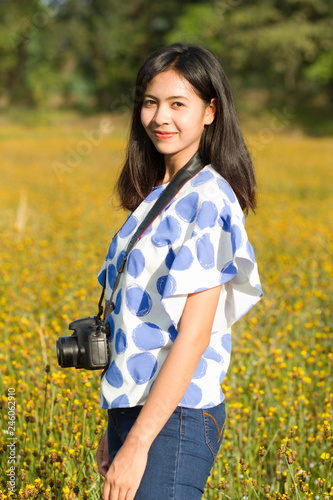Woman holding camera in yellow flower field