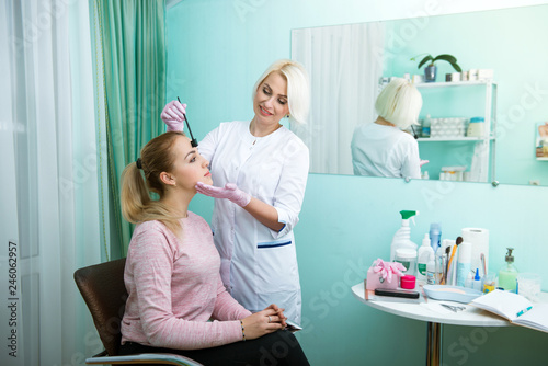 Young woman undergoing procedure of eyebrow permanent makeup in beauty salon. face care