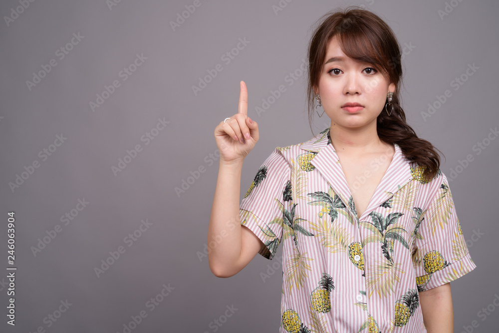 Asian tourist woman pointing finger and showing copyspace Asian tourist woman pointing finger and showing copyspace