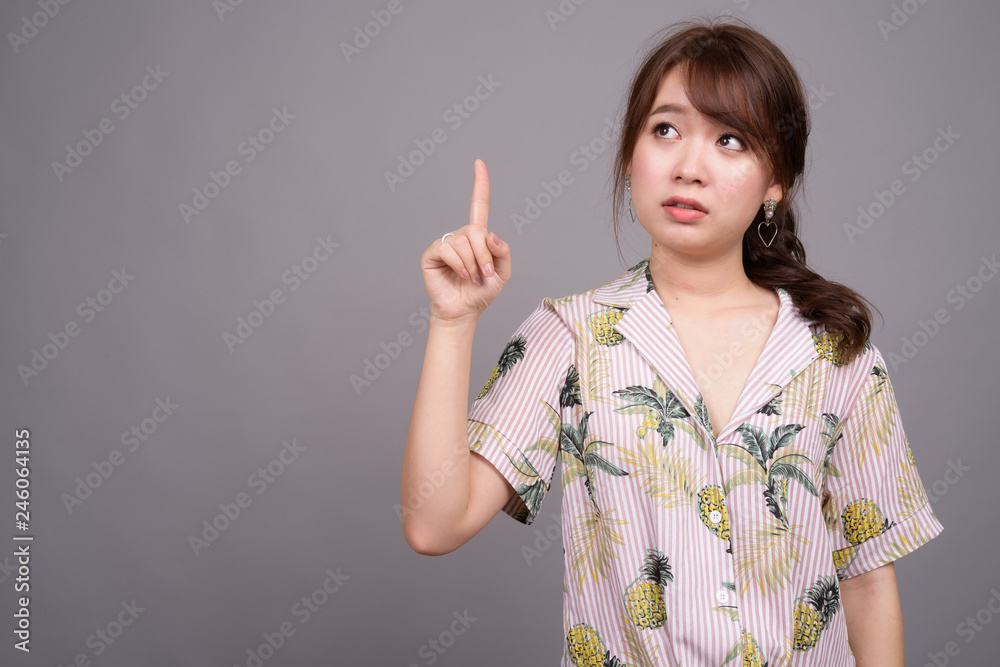 Asian tourist woman pointing finger and showing copyspace