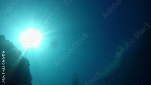 Freediver slowly descending from surface to bottom of Lake Ohrid in Macedonia in very clear and transparent water. Shot from bottom with view of a sun. photo