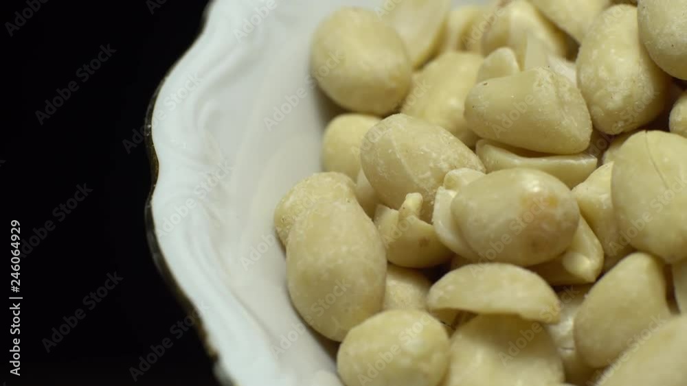 Raw peeled peanuts. Rotation. Snack closeup. Peanuts in a bowl. Selective focus. black background. Studio shot. Healthy food concept. Raw peeled peanuts. Rotation. Snack closeup. Peanuts in a bowl. Selective focus. black background. Studio shot. Healthy food concept.