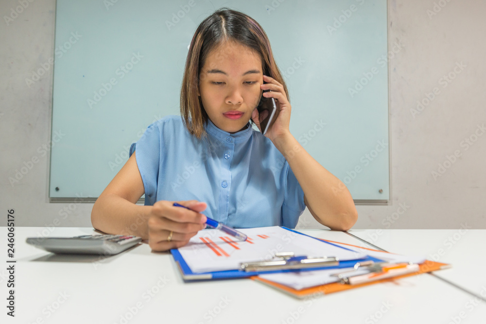 Young Asian office manager talking on phone about the finance Young Asian office manager talking on phone about the finance