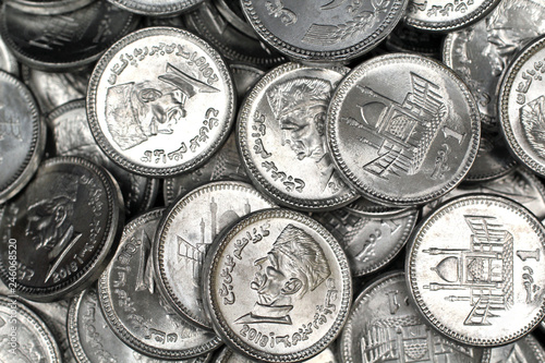 A close up image of a pile of silver Pakistani one rupee silver coins