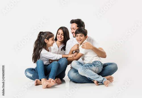 Fotografie Playful Indian/asian family sitting isolated over white background