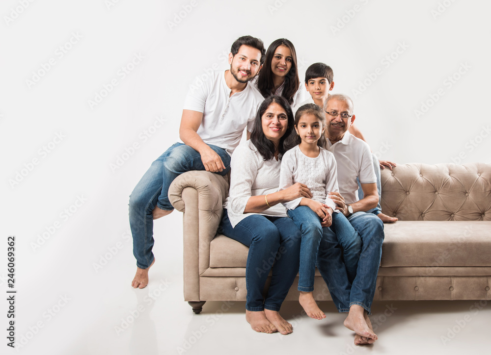 Indian/asian family sitting on sofa or couch over white background Stock  Photo | Adobe Stock