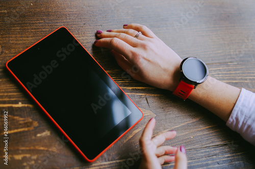 Business woman working on her coffee break in a cafe, hands of woman wearing smartwatch and holding tablet . Female hands touching screen. Close up.