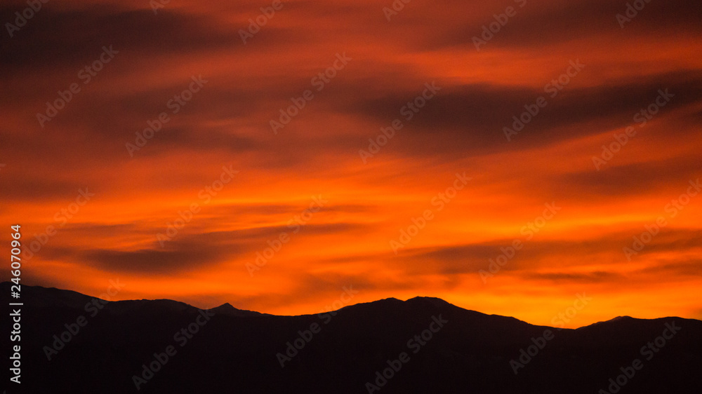 Red and Orange Sunset with Mountain Silhouette and Clouds Red and Orange Sunset with Mountain Silhouette and Clouds