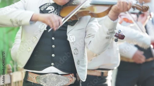 three mexican mariachis with white mariachi costume playing the violin at a mexican party