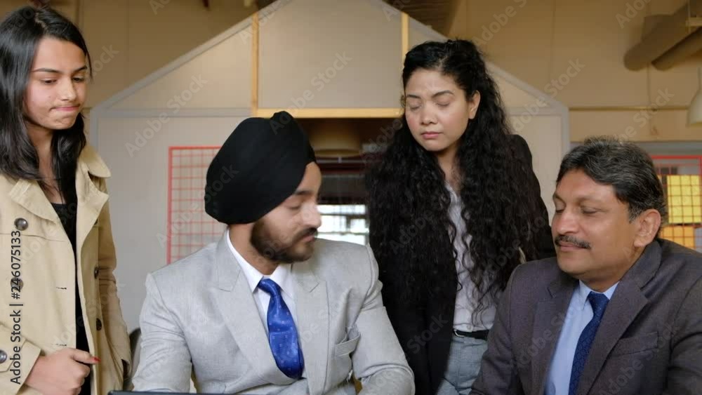 A turbaned boss looks disdainfully at his senior and junior colleague and he smiles sarcastically, as he tries to make them understand and comprehend on a touch screen tablet A turbaned boss looks disdainfully at his senior and junior colleague and he smiles sarcastically, as he tries to make them understand and comprehend on a touch screen tablet