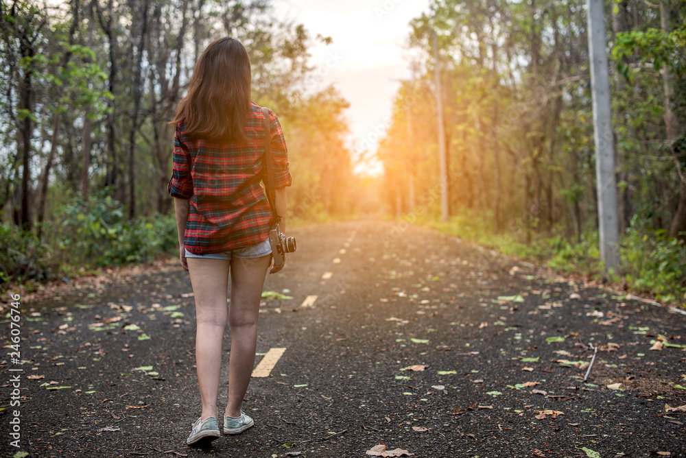 Beautiful woman with retro camera on the street in the forest alone.
