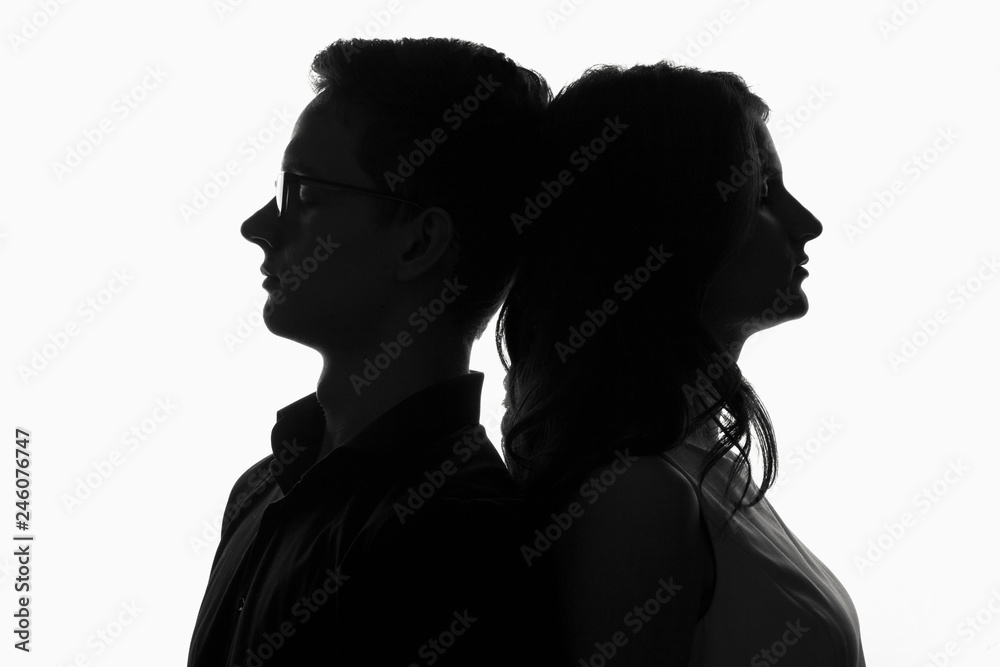 silhouette of a couple, young girl and a guy leaned against each other head