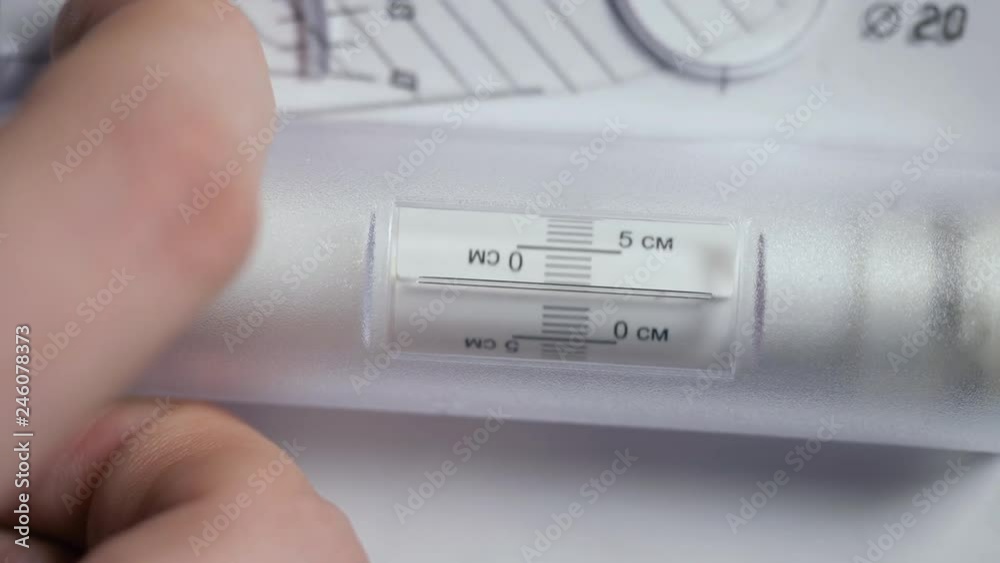closeup engineer checks part drawing with spinning ruler