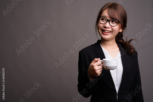 Young beautiful Asian businesswoman holding coffee cup