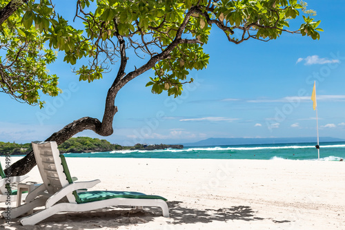 Chaise lounges on the beautiful tropical beach with white sand. Bali island. Indonesia.