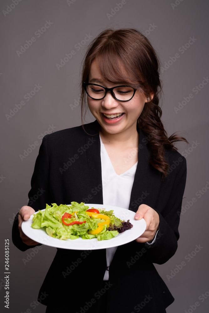 Happy Asian businesswoman holding salad while smiling Happy Asian businesswoman holding salad while smiling