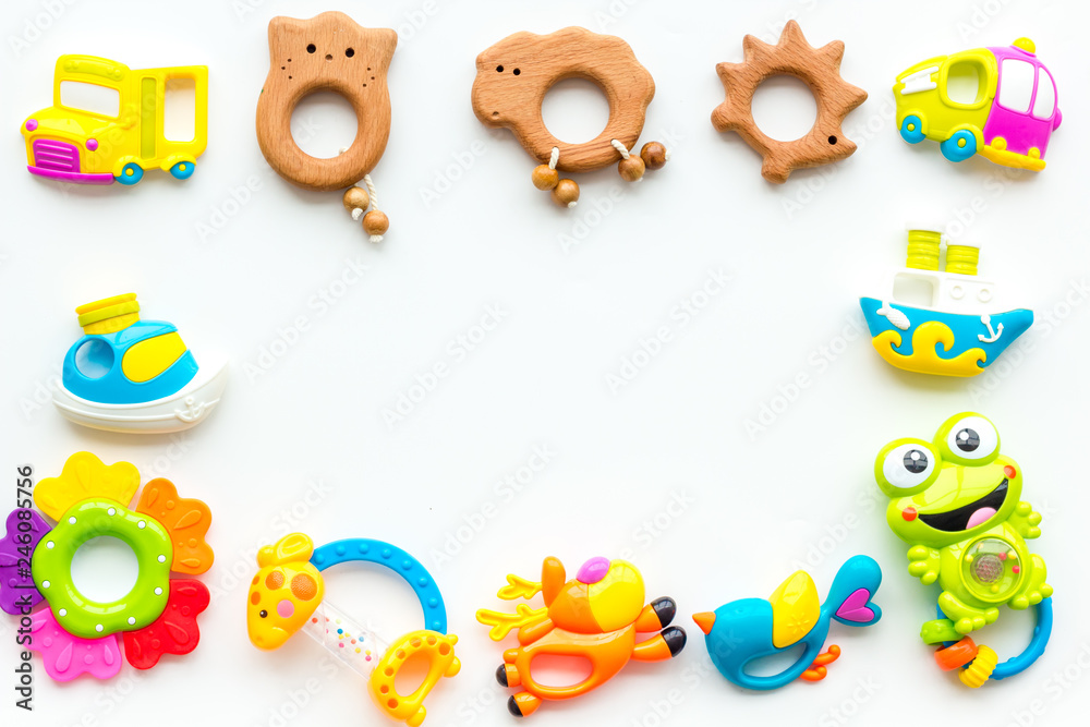 Handmade toys for newborn babies, plastic and wooden rattle on white background top view space for text frame