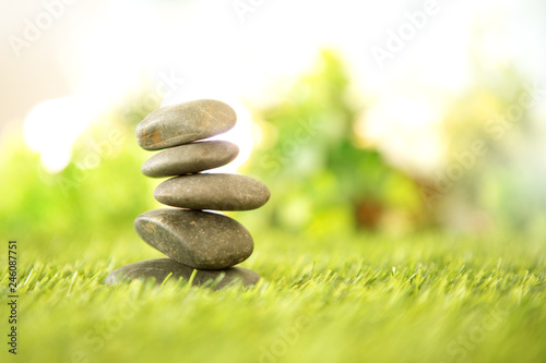balance with pyramid of stone on fresh nature green grass , spa meditation or well-being with zen concept