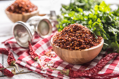 Dried and crushed chili peppers in wooden bowles with parsley herbs