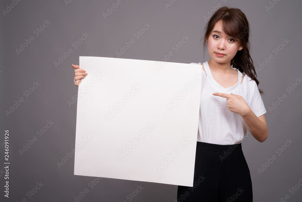 Asian woman showing empty white board with copyspace Asian woman showing empty white board with copyspace