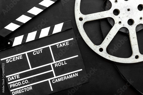 Filmings concept. Clapperboard and film stock on black background top view copy space
