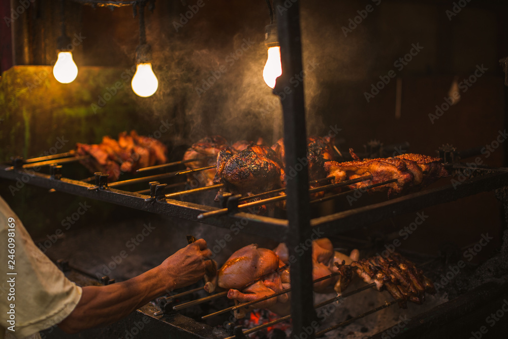 outdoor street chicken barbecue grill arm and hand brush oiling the