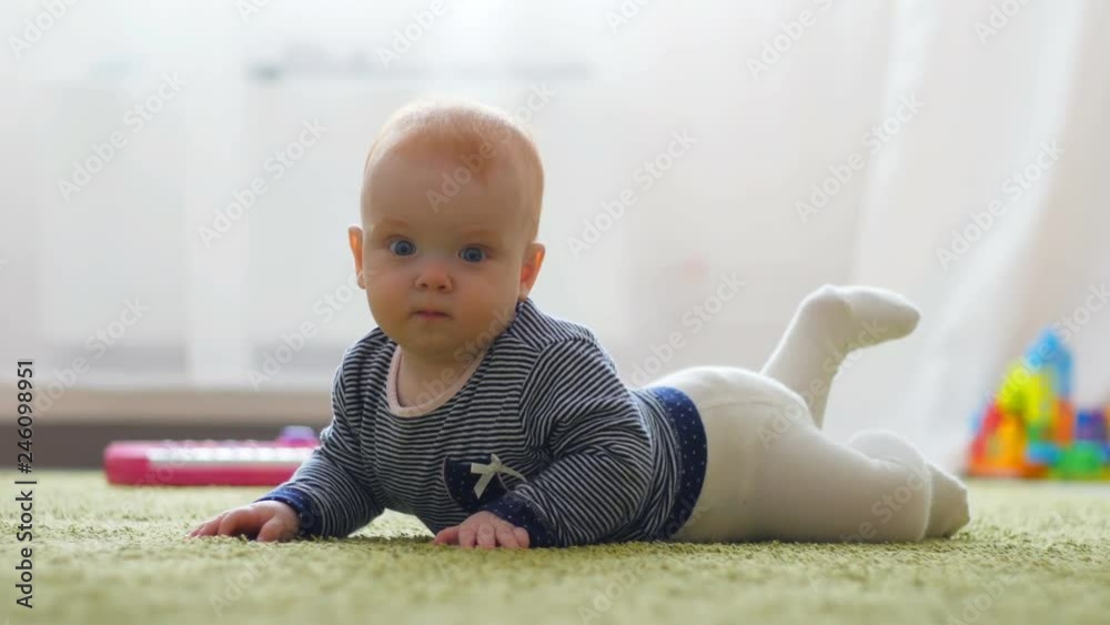 The baby girl learns to crawl, the first attempts to crawl. Baby crawls to the camera, smiling and laughing on the floor in the white room The baby girl learns to crawl, the first attempts to crawl. Baby crawls to the camera, smiling and laughing on the floor in the white room