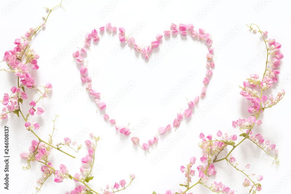 flat lay of floral heart made from pink flowers isolated on white background with pink flower border frame, top view. flower creative composition