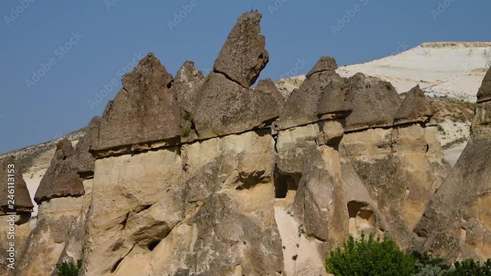 Close up low angle tilt up of similar erect-topped cone-shaped rock ...