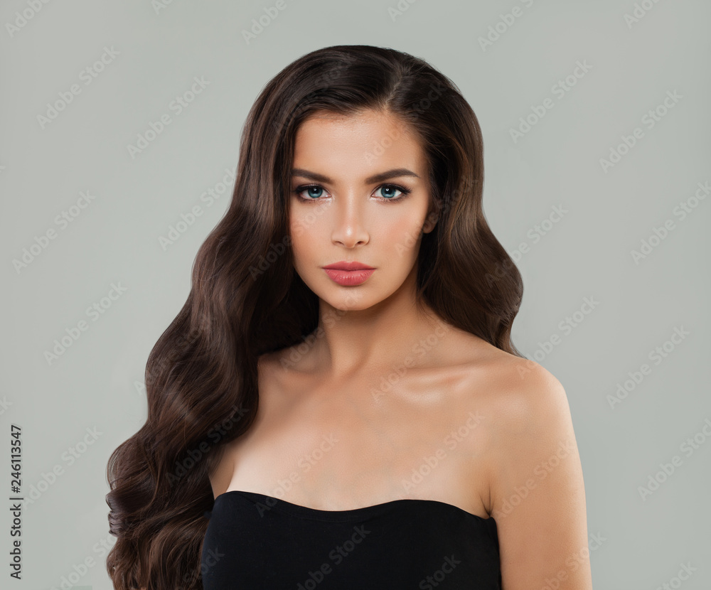 Naklejka premium Portrait of young woman with brown hair. Hair care and beauty girl portrait on gray background