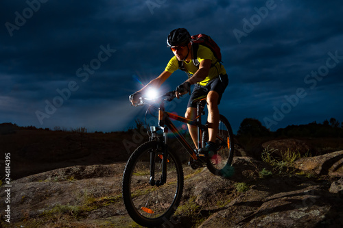Cyclist Riding the Mountain Bike on Rocky Trail at Night. Extreme Sport and Enduro Biking Concept. © Maksym Protsenko
