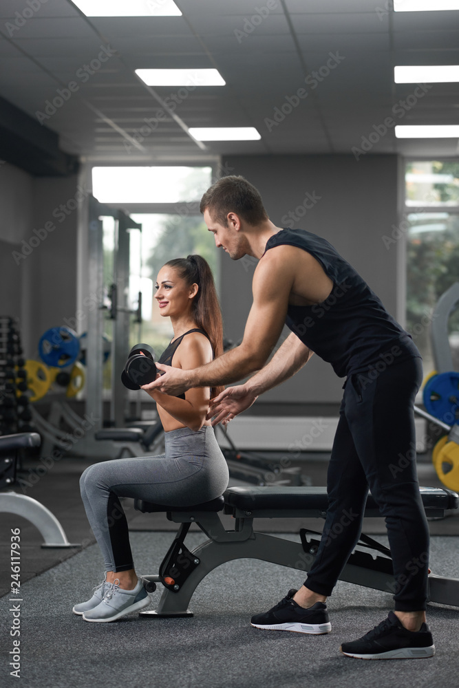 Handsome helping sporty girl going exercises.