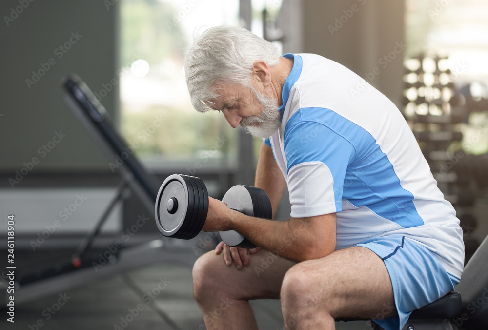Fit elderly man working out with dumbbells in gym. Stock Photo Adobe Stock