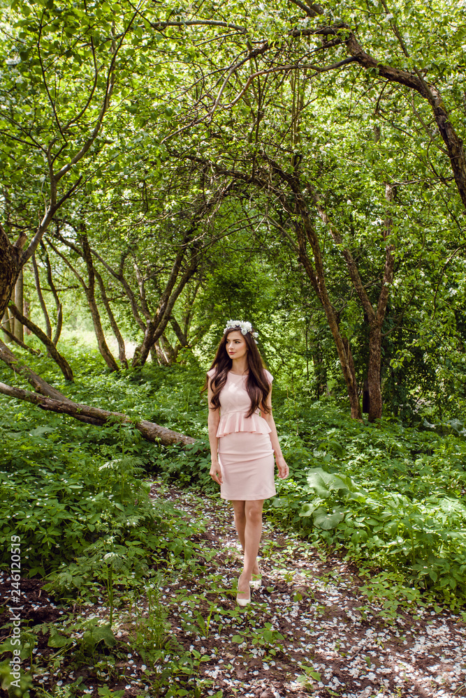 Cute young woman in pink dress standing in flowers garden outdoors. Beautiful girl outdoor portrait Cute young woman in pink dress standing in flowers garden outdoors. Beautiful girl outdoor portrait