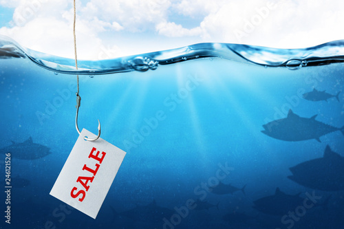 The inscription sale on the sheet as bait for buyers. Fishing hook with fish bait as symbol of deception. Blue underwater sea background. photo