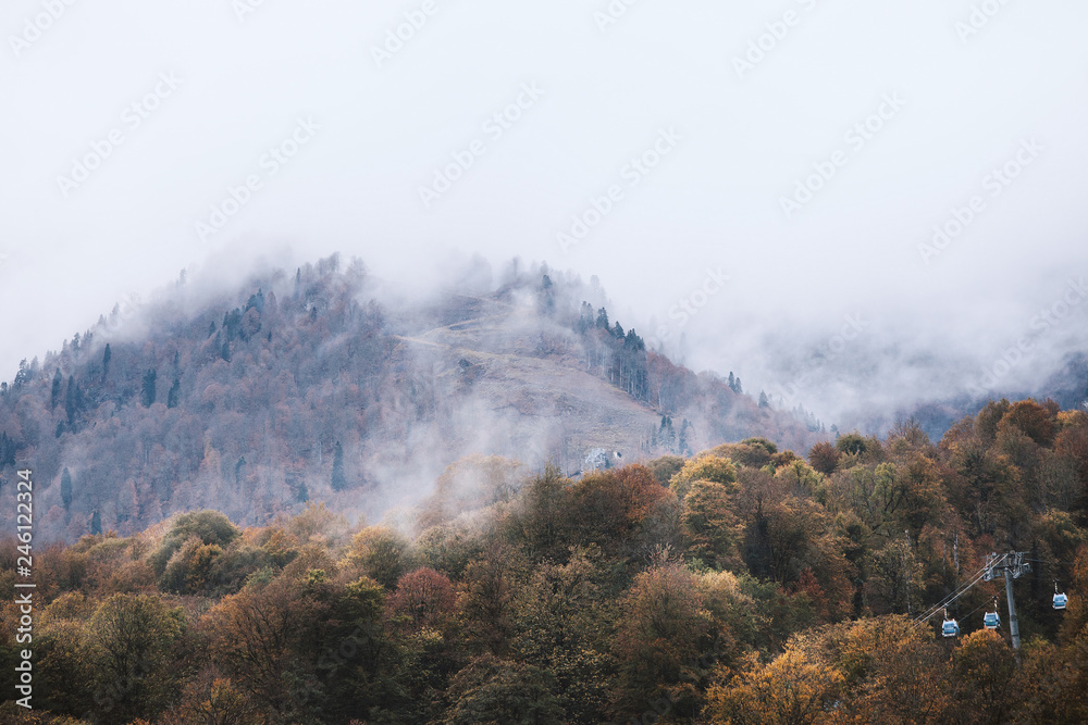 Beautiful picturesque view of a hilly mountain covered with white fog and forest. Concept of vacation in a picturesque resort in the city of clean mountain air. Copyspace