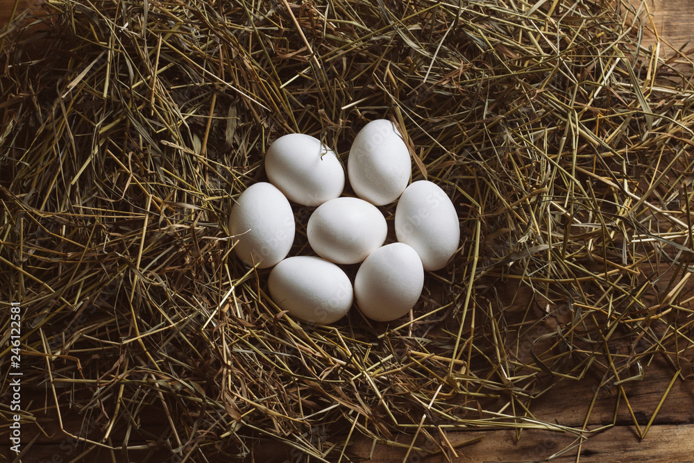 White Chicken Eggs on a hay on a wooden background. The concept of the Farm Product. Flat lay, top view
