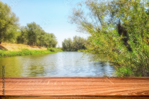 Empty wooden table with summer background of riverside in the daytime for display or montage products
