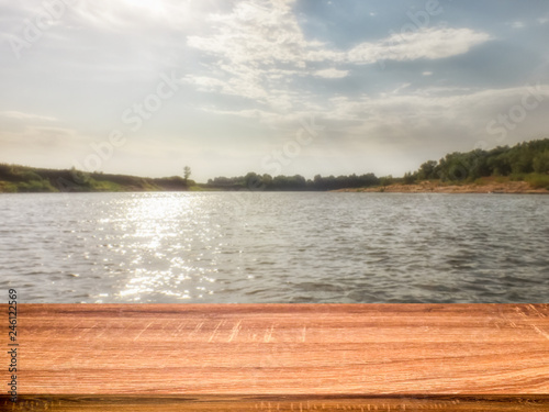 Empty wooden table with blurred summer background of riverside in the daytime for display or montage products